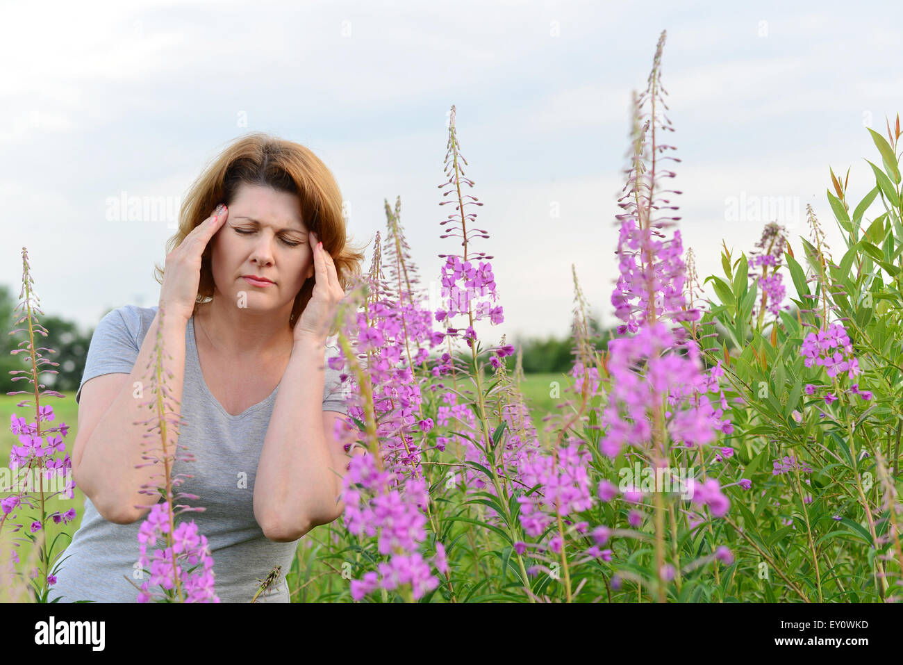 Portrait de femme avec des maux de tête près de Willow-herb dans le domaine Banque D'Images