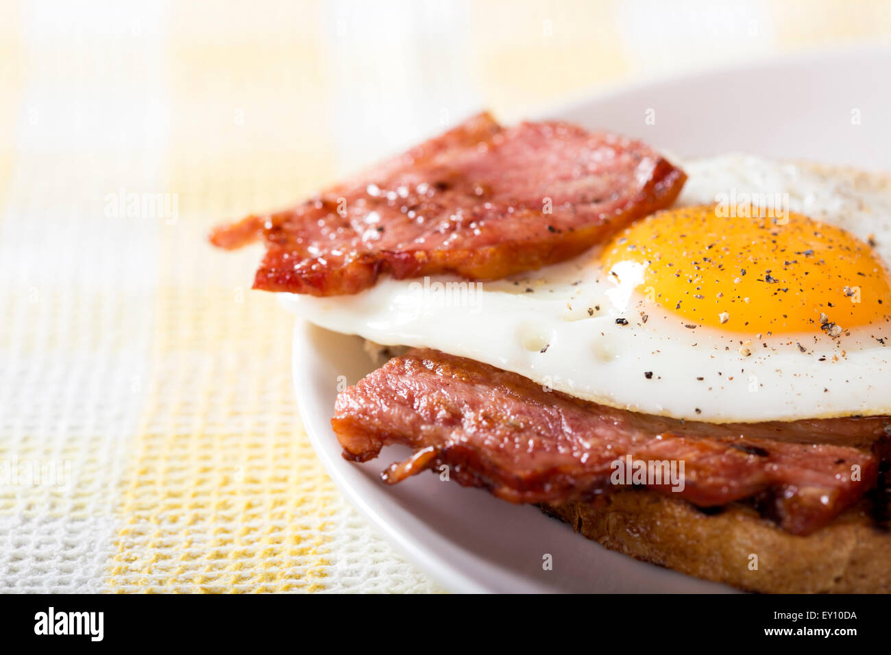 Toast avec les œufs et le bacon sur une assiette blanche Banque D'Images