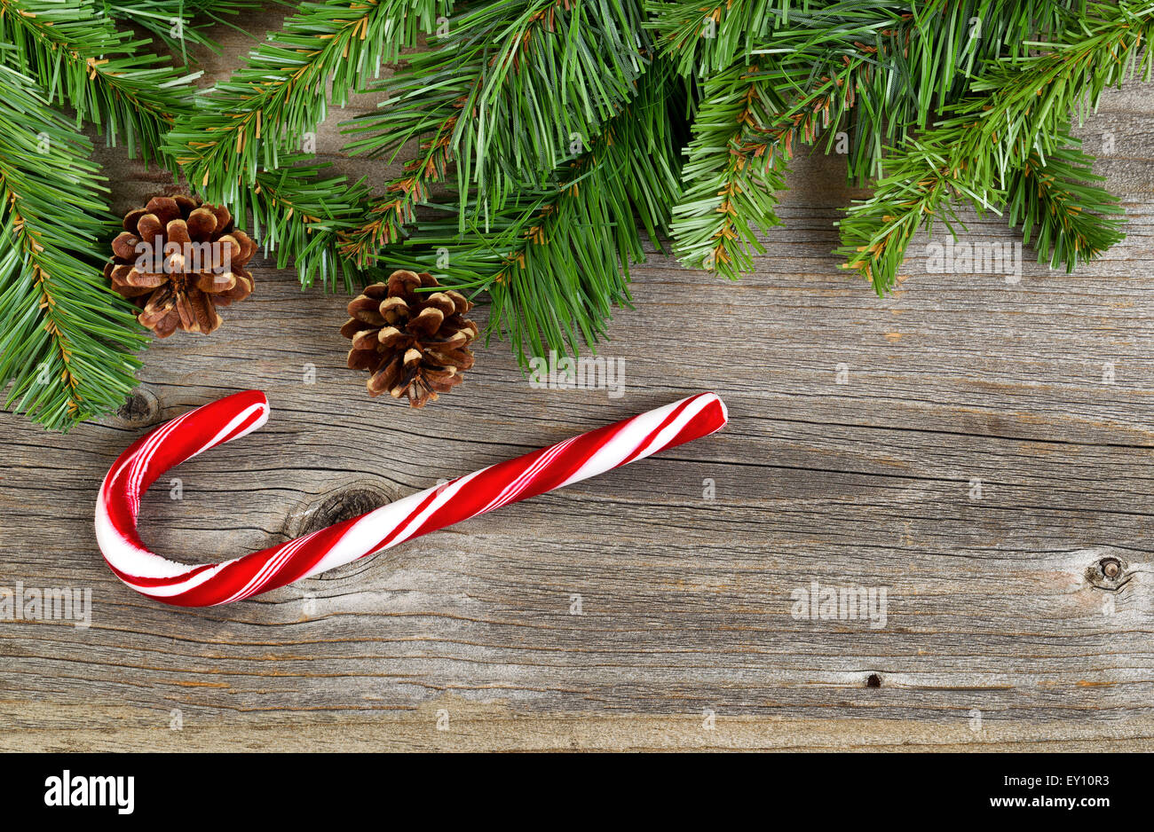 Frontière de Noël avec des branches d'arbre de pin, cônes et une seule grande canne rustique sur les planches de bois. Banque D'Images