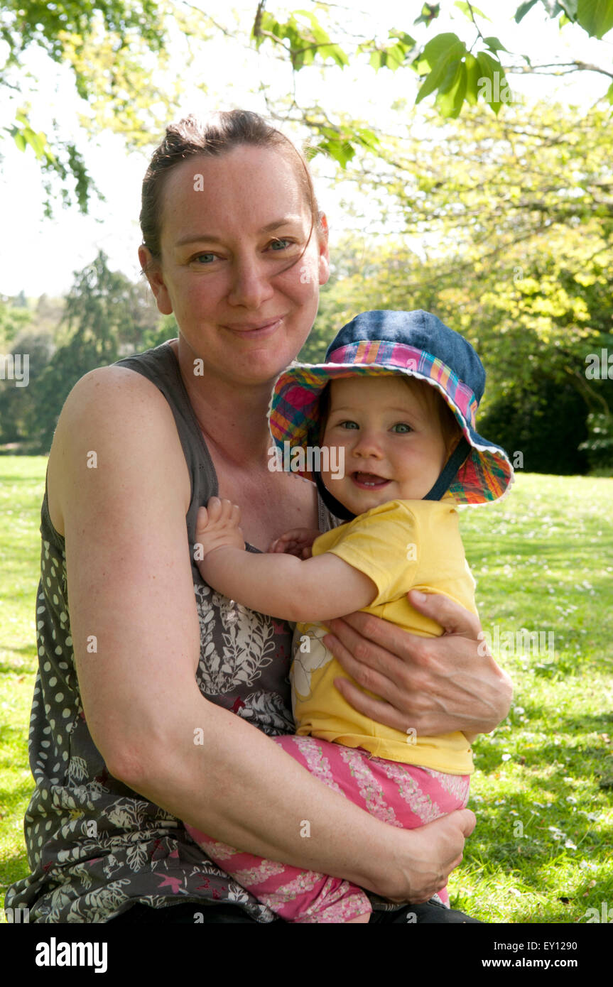 Mère de câliner son bébé dans le le jardin sur une belle journée d'été Banque D'Images
