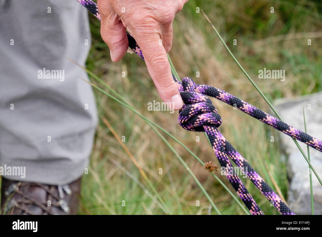Rock climber démontrant l'enveloppant d'un nœud double dans une corde d'assurage escalade. Royaume-uni, Angleterre Banque D'Images