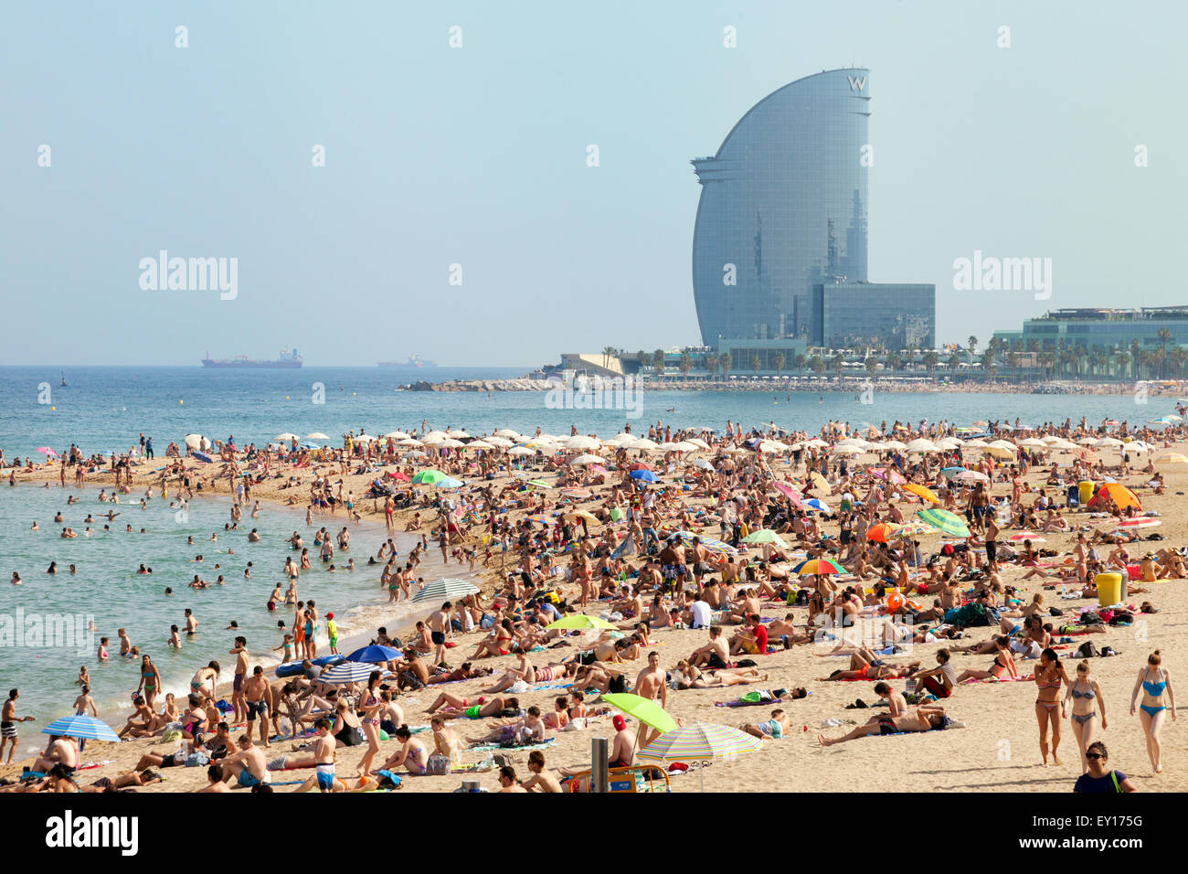 Des foules de gens en train de bronzer sur la plage de Barceloneta, Platya de la Barceloneta, avec en arrière-plan, Barcelone, Espagne Europe Banque D'Images