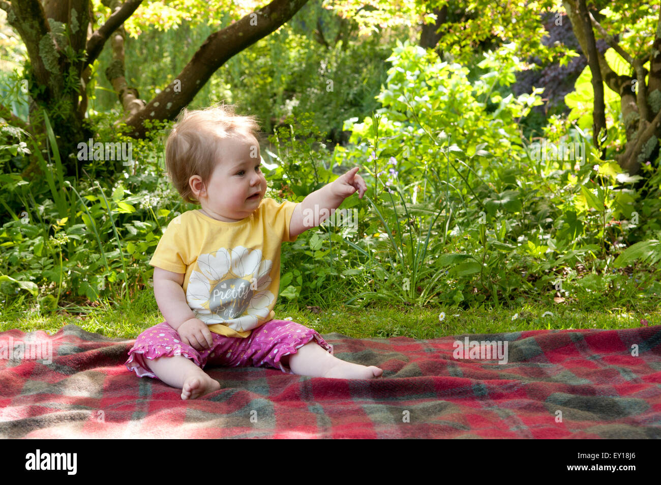 Baby Girl sitting sans aide sur un tapis vers Banque D'Images