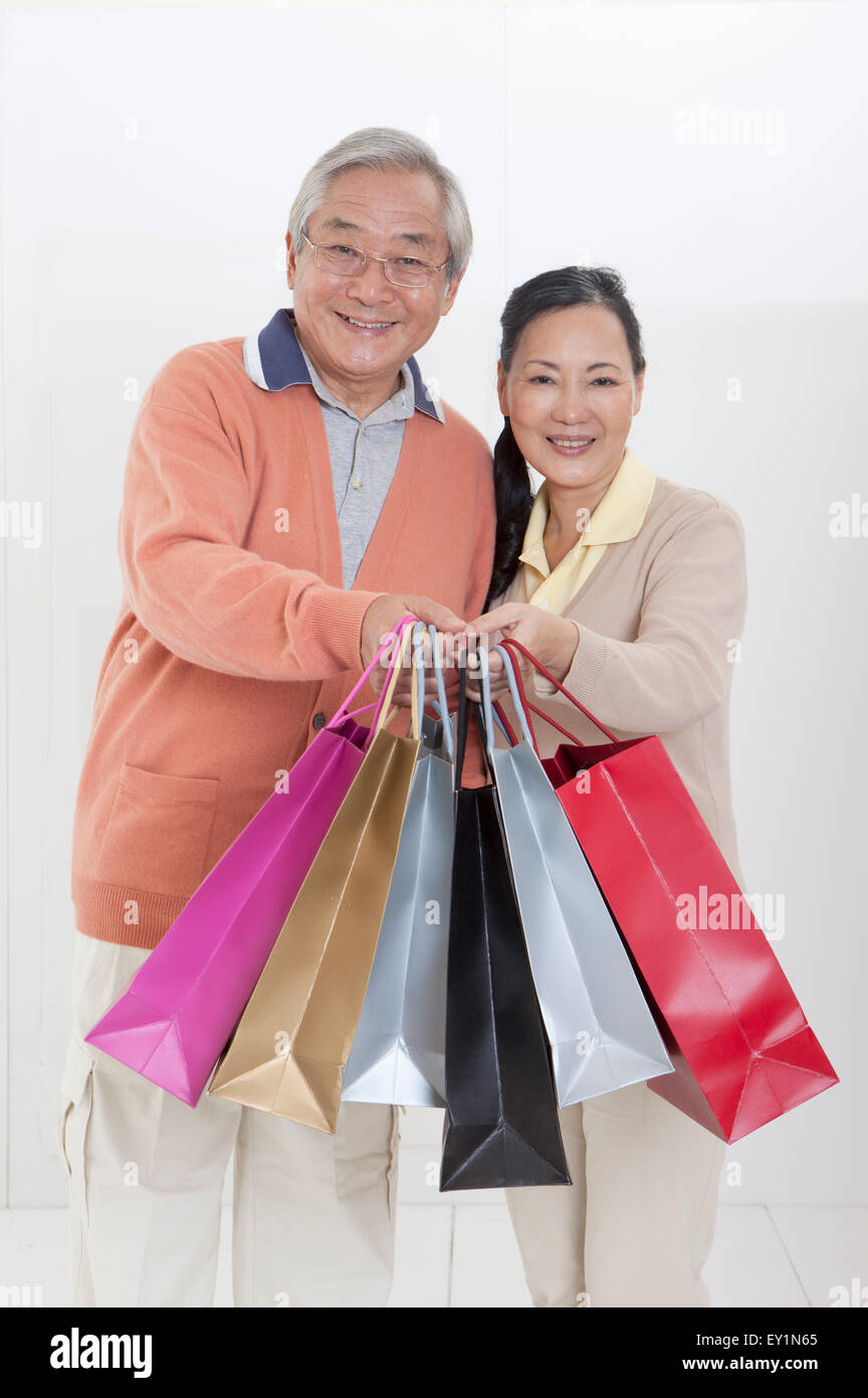 Senior couple holding shopping bags and smiling joyeusement à l'appareil photo, Banque D'Images