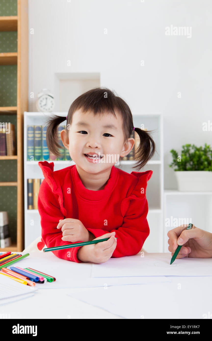 Little girl holding crayon de couleur et souriant à la caméra, Banque D'Images