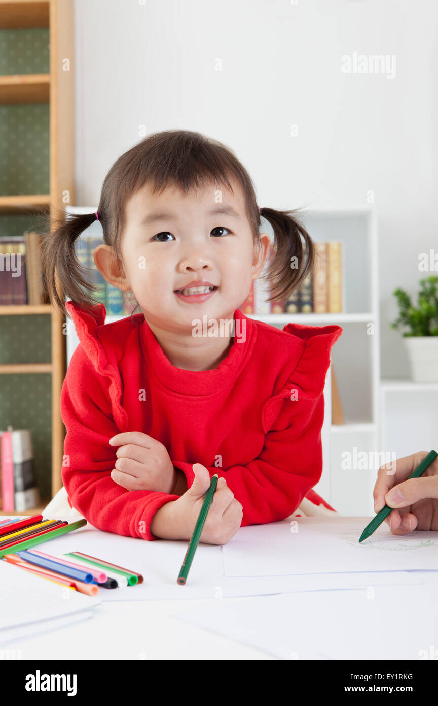 Little girl holding crayon de couleur et à la recherche jusqu'à sourire, Banque D'Images