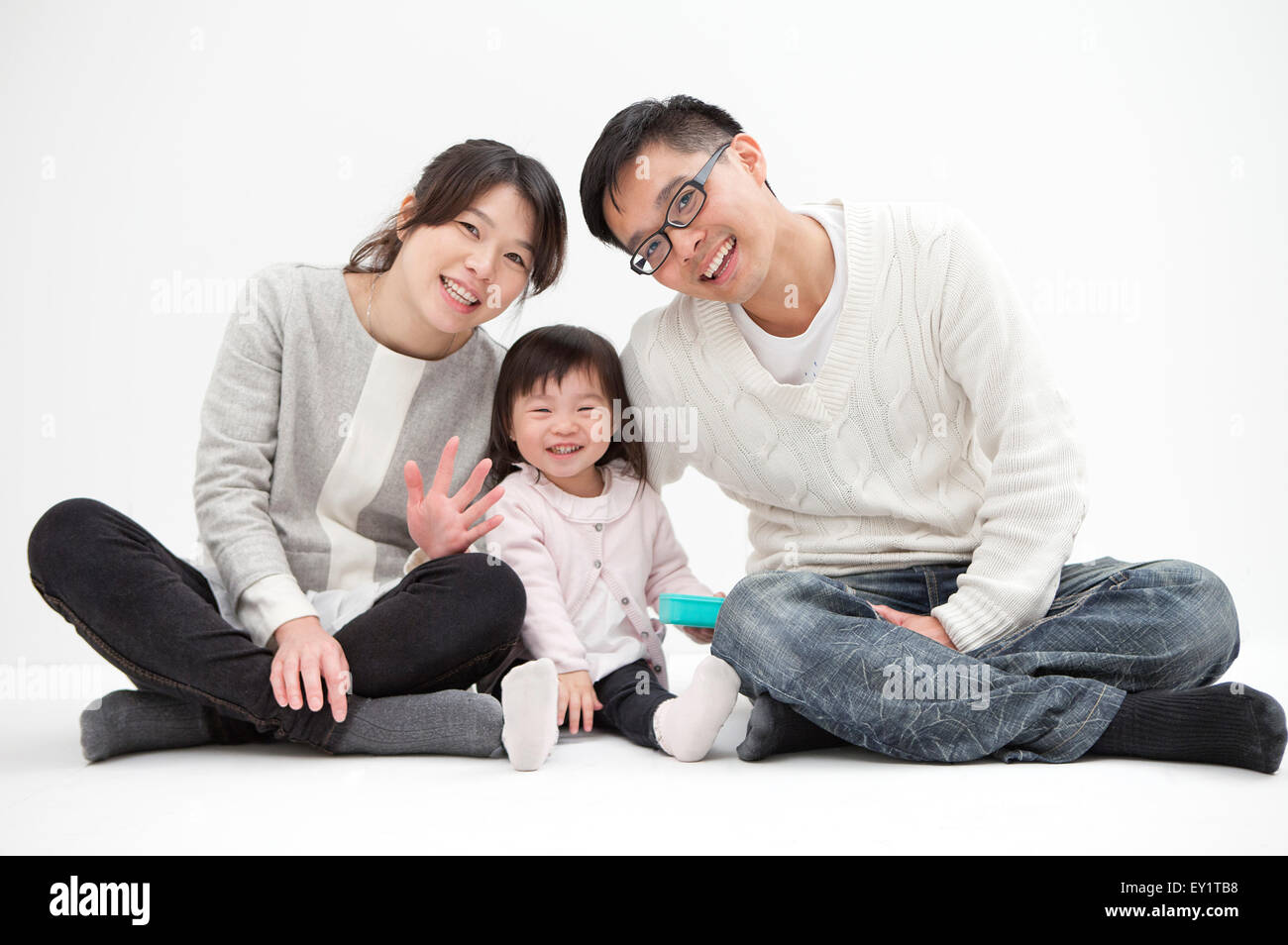 Famille avec un enfant assis et souriant à l'ensemble, l'appareil photo Banque D'Images