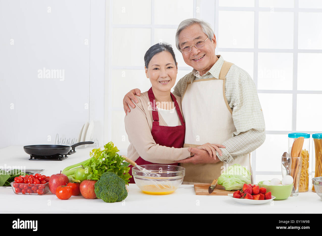 Couple debout dans la cuisine et sourit joyeusement, Banque D'Images
