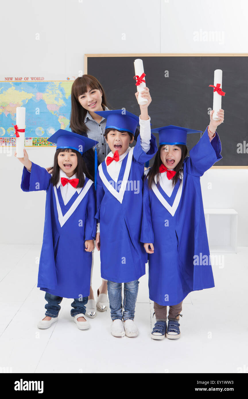 Jeune Enseignant et élèves de toges avec holding diploma avec sourire ensemble, Banque D'Images