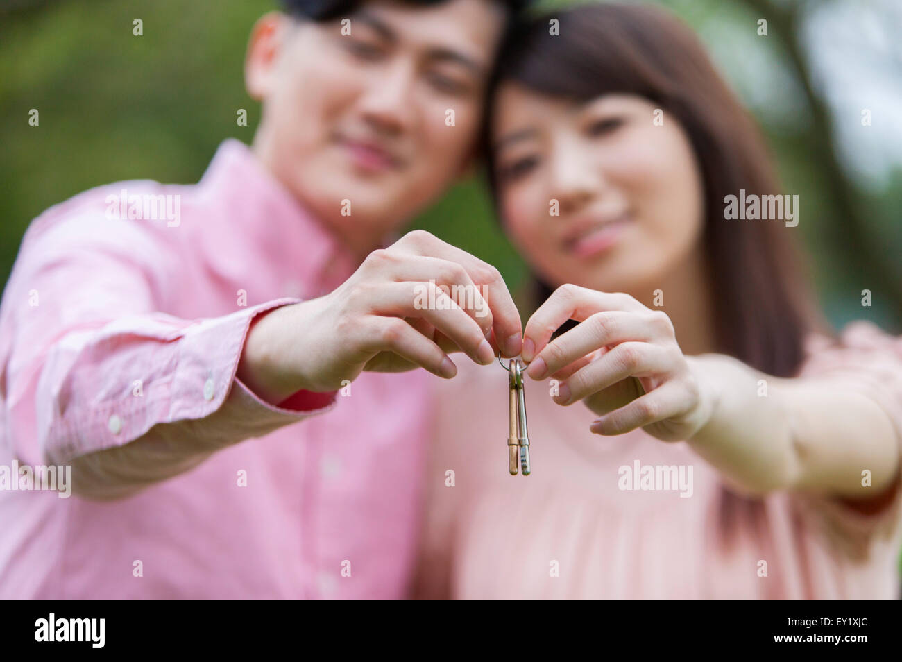 Jeune homme et femme enceinte tenant une clé et souriant à l'ensemble, l'appareil photo Banque D'Images