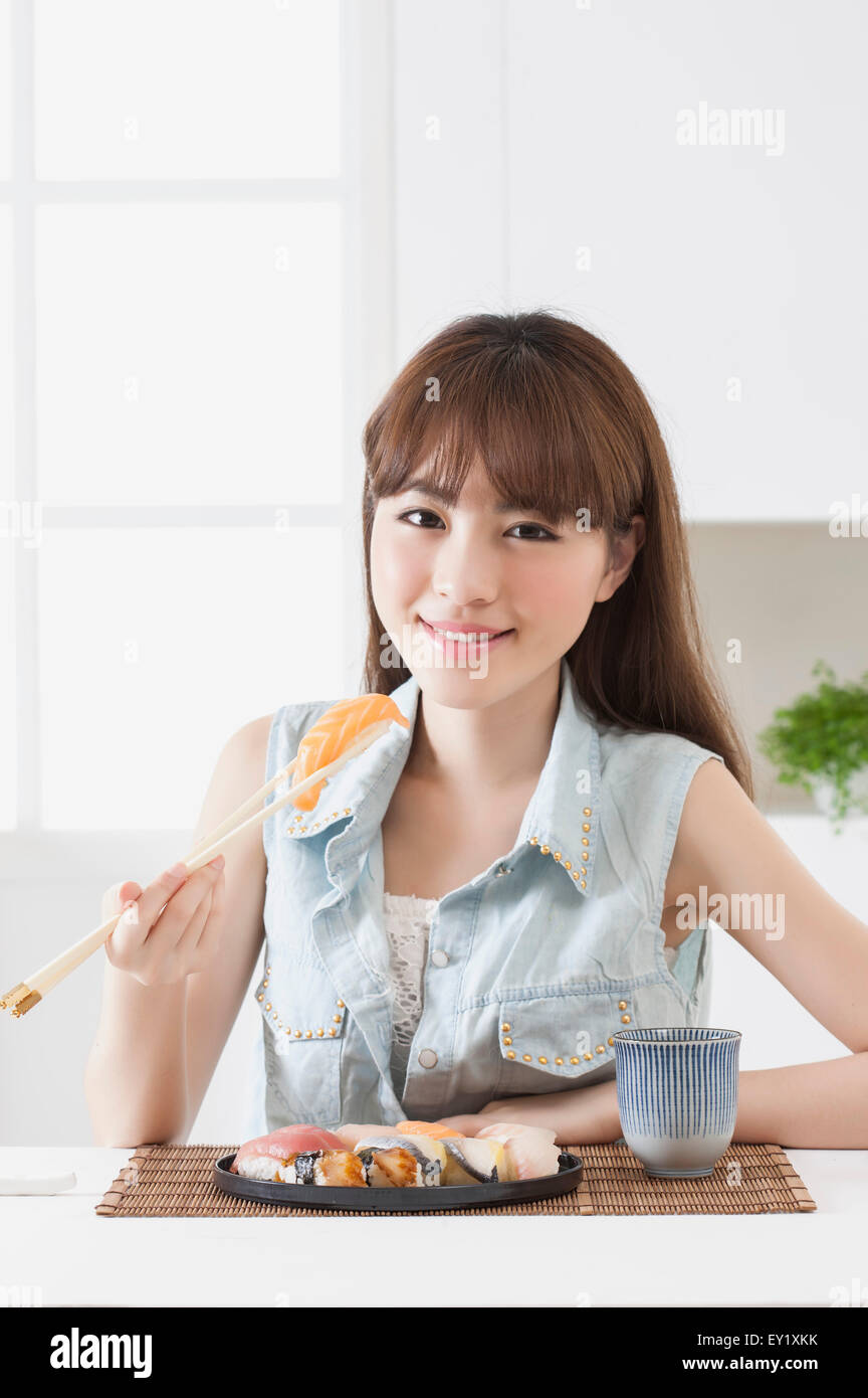 Young woman holding sashimi et souriant à la caméra, Banque D'Images