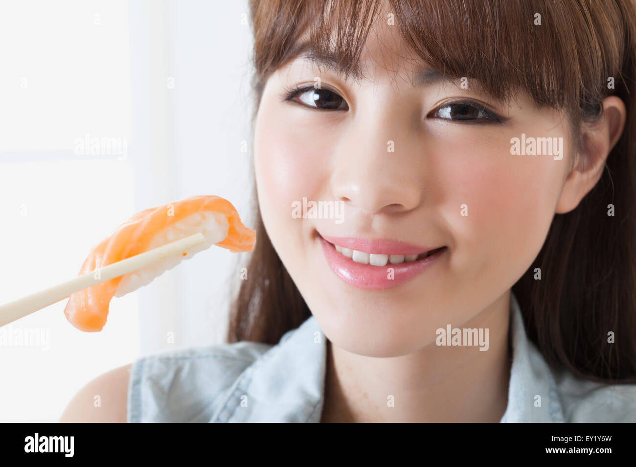 Young woman holding sashimi et souriant à la caméra, Banque D'Images