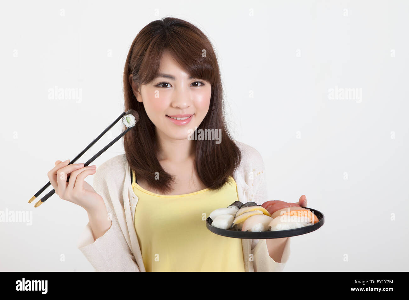 Jeune femme tenant les baguettes et une assiette de nourriture japonaise avec sourire, Banque D'Images
