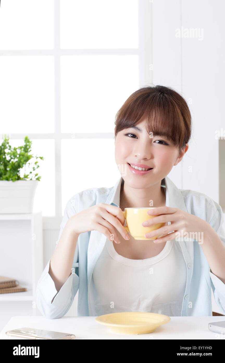 Jeune femme tenant une tasse de café et souriant à la caméra, Banque D'Images