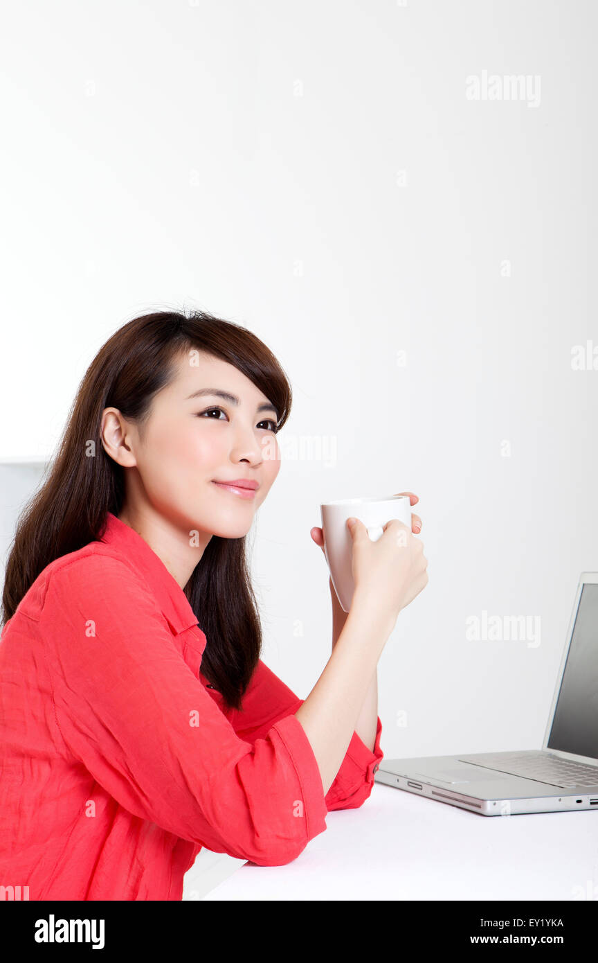 Jeune femme tenant une tasse de café et à l'écart avec sourire, Banque D'Images