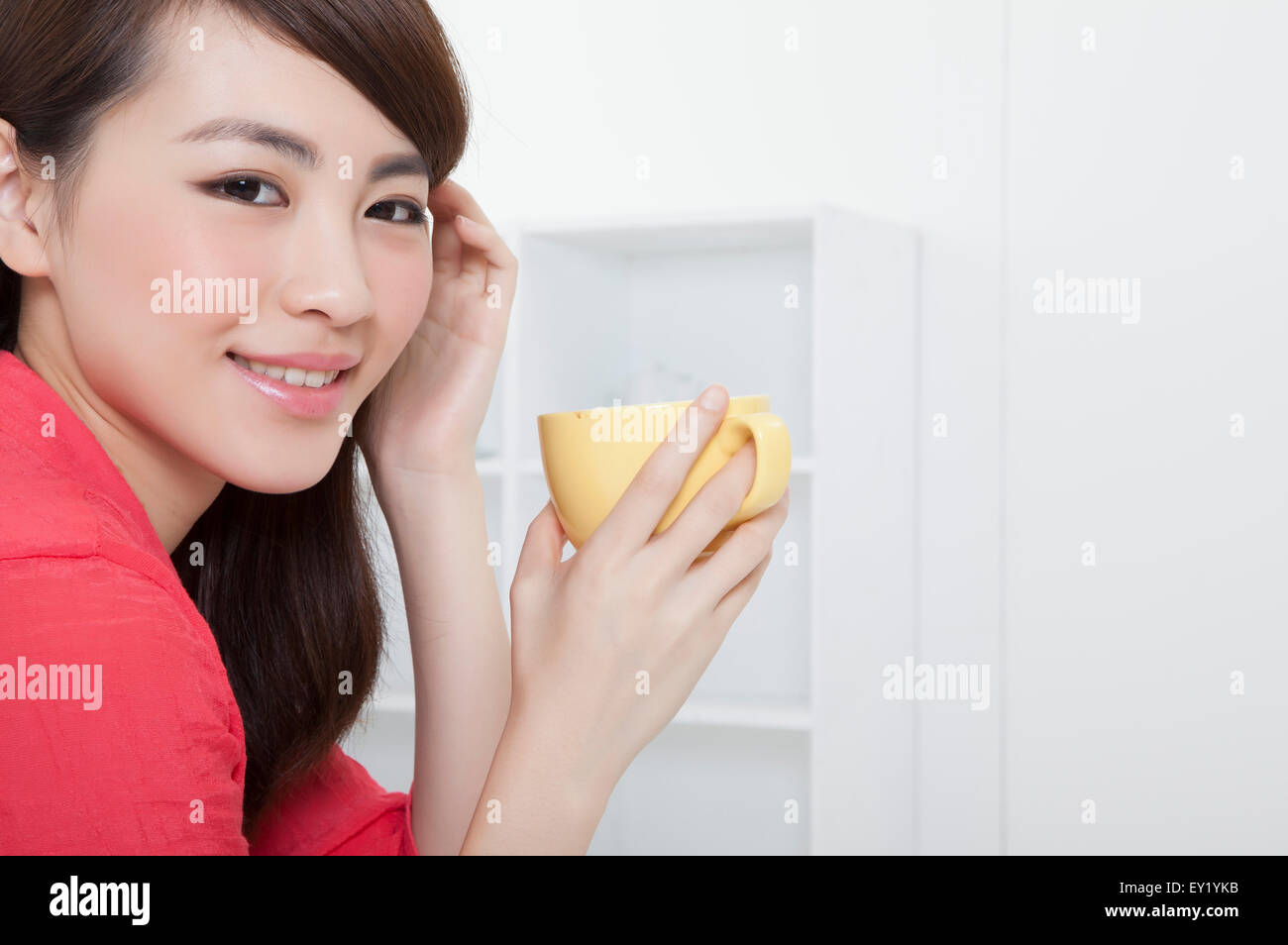 Jeune femme tenant une tasse de café et souriant à la caméra, Banque D'Images