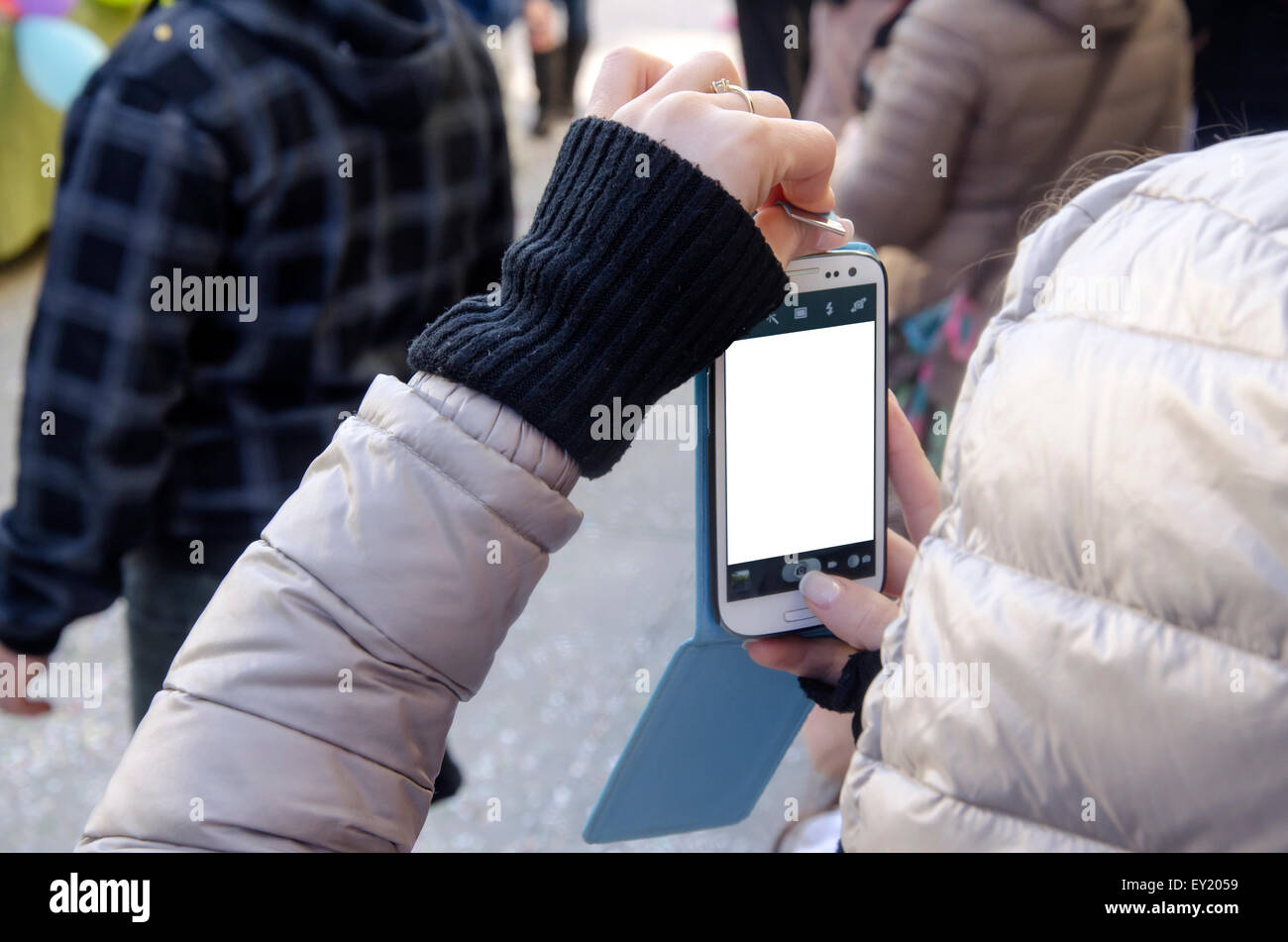Les mains des femmes de prendre photo avec le smartphone et l'écran blanc parmi les gens sur février 28,2015 à Villasimius, Italie Banque D'Images