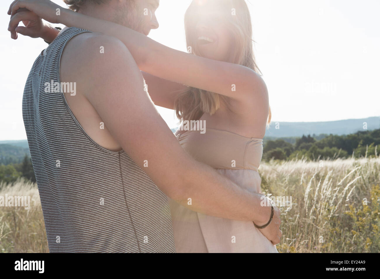 Jeune femme enceinte et petit ami hugging in field Banque D'Images