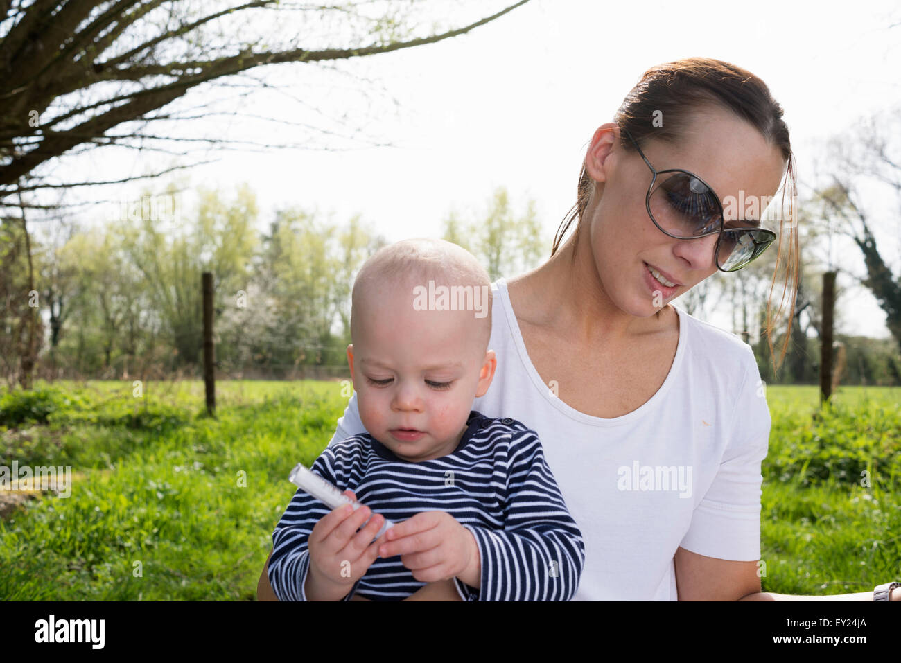 Baby Boy sitting sur les mères lap in field Banque D'Images