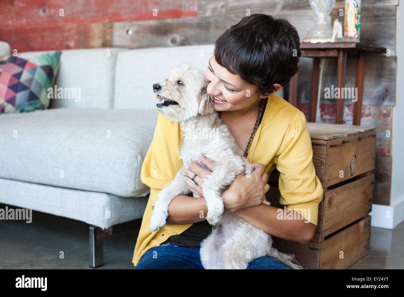 Young woman hugging dog sur le plancher du salon Banque D'Images