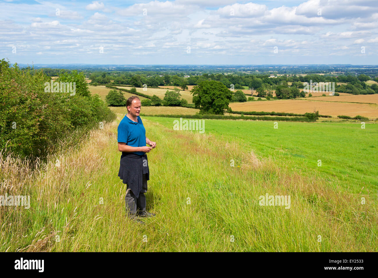 Jeune homme marchant à travers champs près de Malvern, Worcestershire, Angleterre, Royaume-Uni Banque D'Images