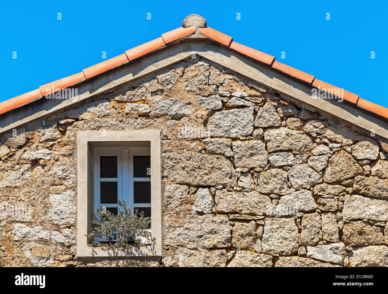 La vie ancienne façade de maison fragment, mur de pierre avec fenêtre sous le toit en tuiles rouges, Corse, France Banque D'Images