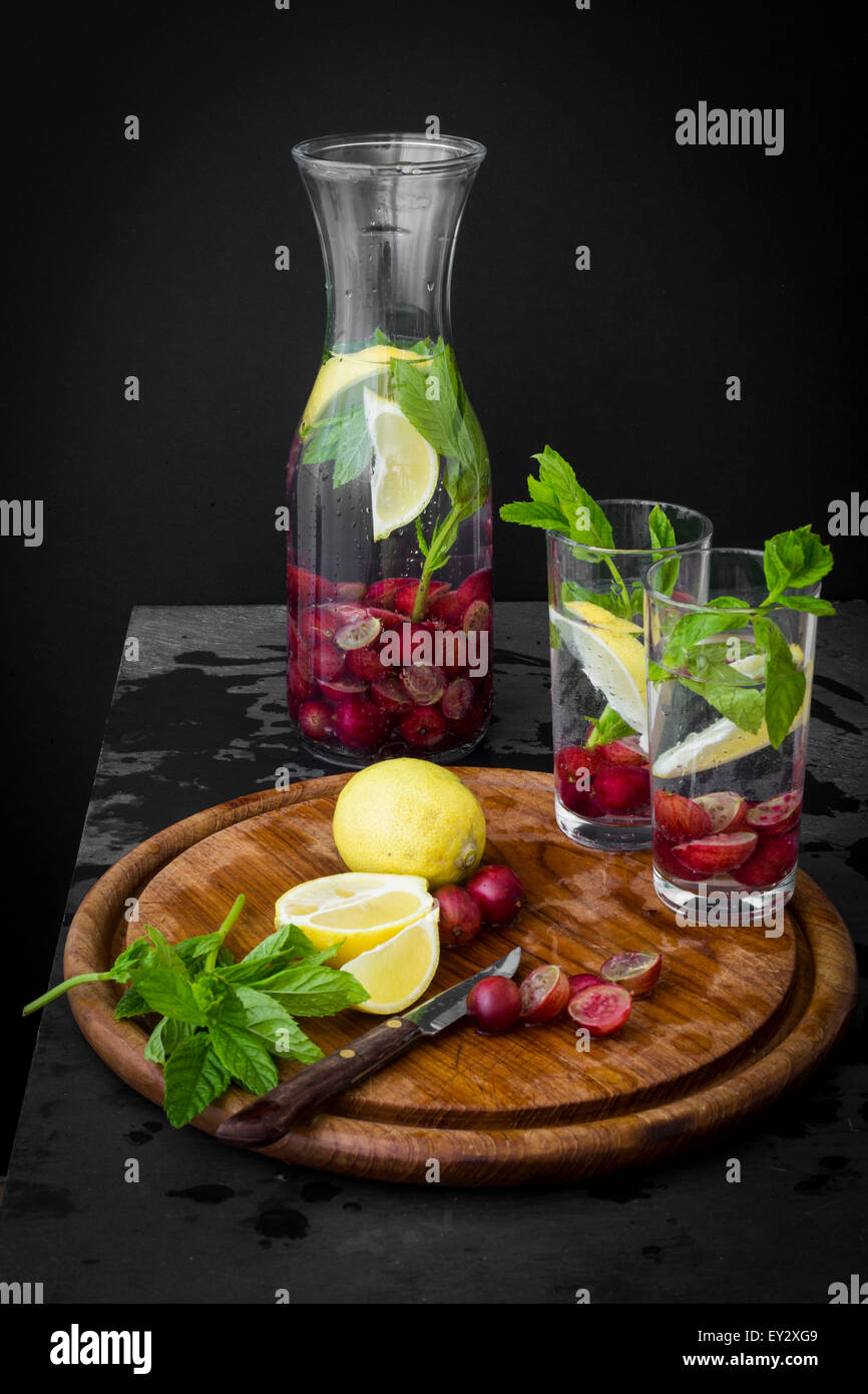 Pichet d'eau avec des fruits et des herbes sur ardoise table avec planche en bois Banque D'Images