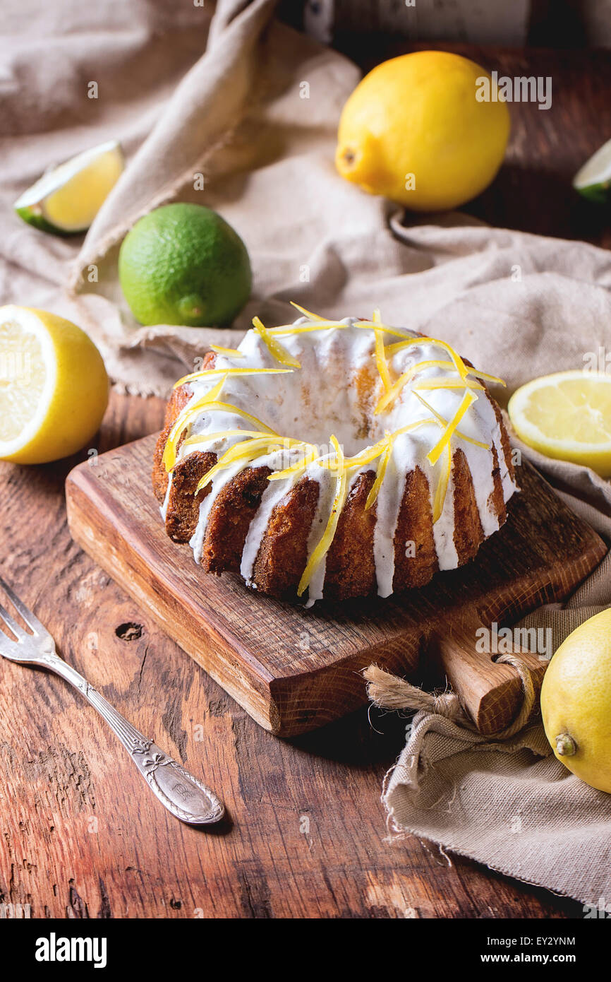 Des gâteaux avec le glaçage blanc et le zeste de citron, servi avec des citrons et de la chaux sur les petites planches en bois sur des zone Banque D'Images