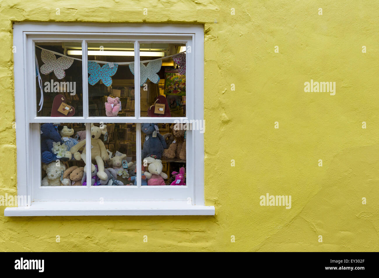 Un assortiment de nounours, lapins et autres animaux en peluche dans une fenêtre pour la vente. Banque D'Images