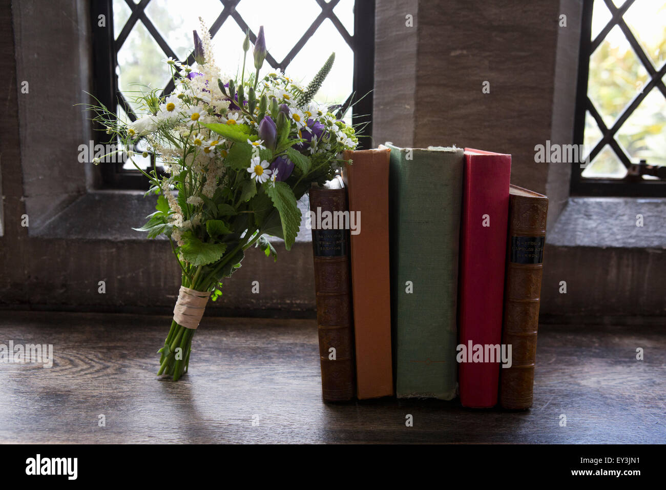 Un bouquet de fleurs de mariage bleu et blanc appuyé contre des livres. Banque D'Images