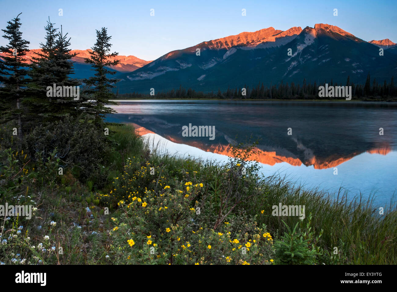 Montagnes reflétée dans un lac et le soleil qui se reflète sur les pentes couvertes de neige. Banque D'Images