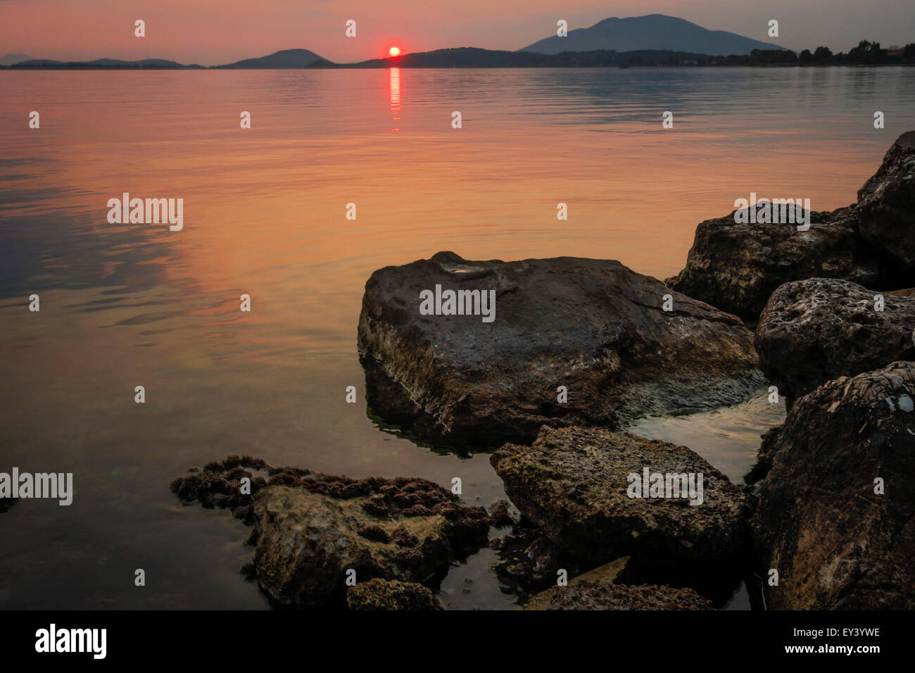 Coucher de soleil sur une mer calme et voir des masses terrestres à l'horizon. Banque D'Images