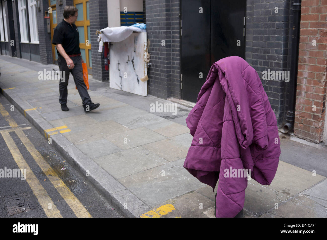 Les gens devant une couette, diffusée sur un poteau dans la rue à Londres, au Royaume-Uni. Une personne sans-abri est composé d'une maison dans les environs de la porte. Banque D'Images