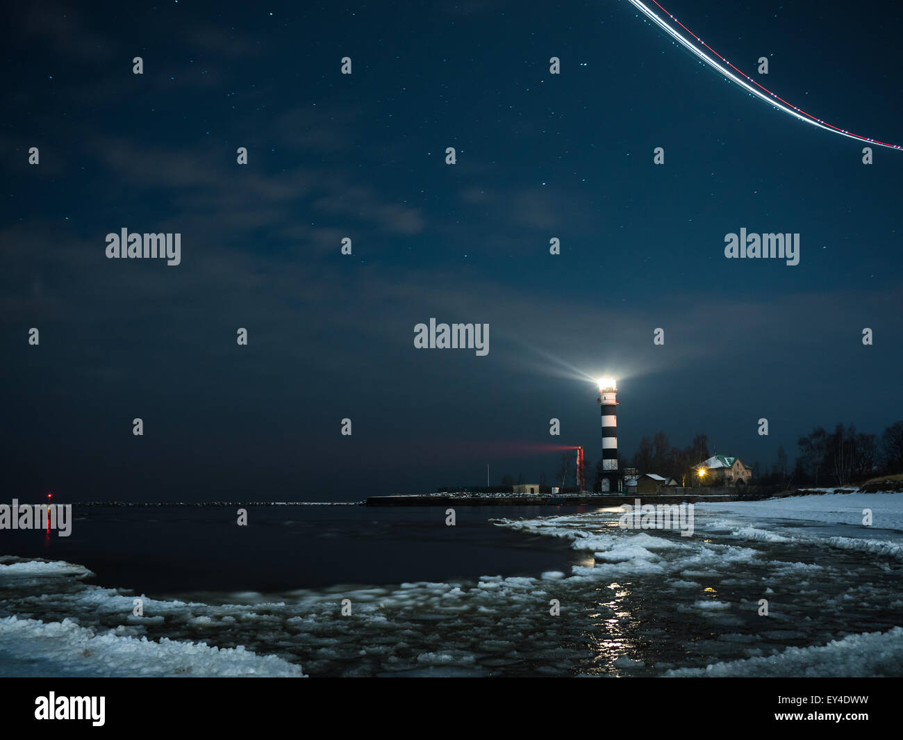 Riga phare dans une nuit étoilée avec la mer Baltique gelée Banque D'Images