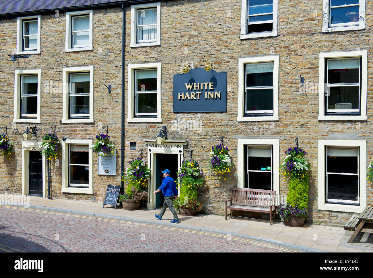 Homme marchant passé le White Hart Inn, dans la région de Hawes, Wensleydale, Yorkshire Dales National Park, North Yorkshire, England UK Banque D'Images