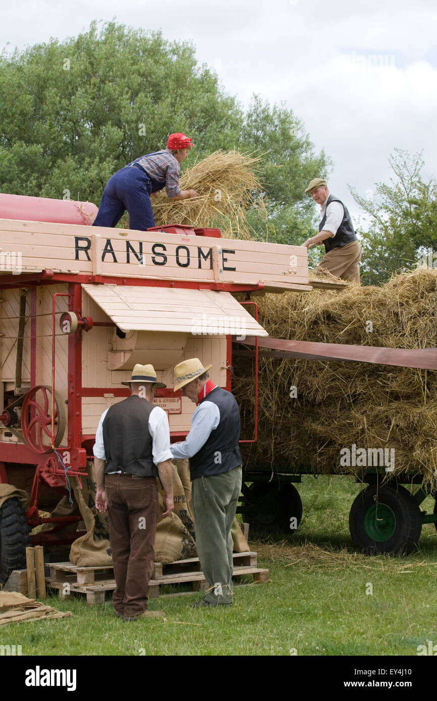Les agriculteurs, hommes et femmes dans l'agriculture traditionnelle en paille chargement de vêtements une ramasseuse-presse à balles, Jones lors d'une démonstration show ground Banque D'Images