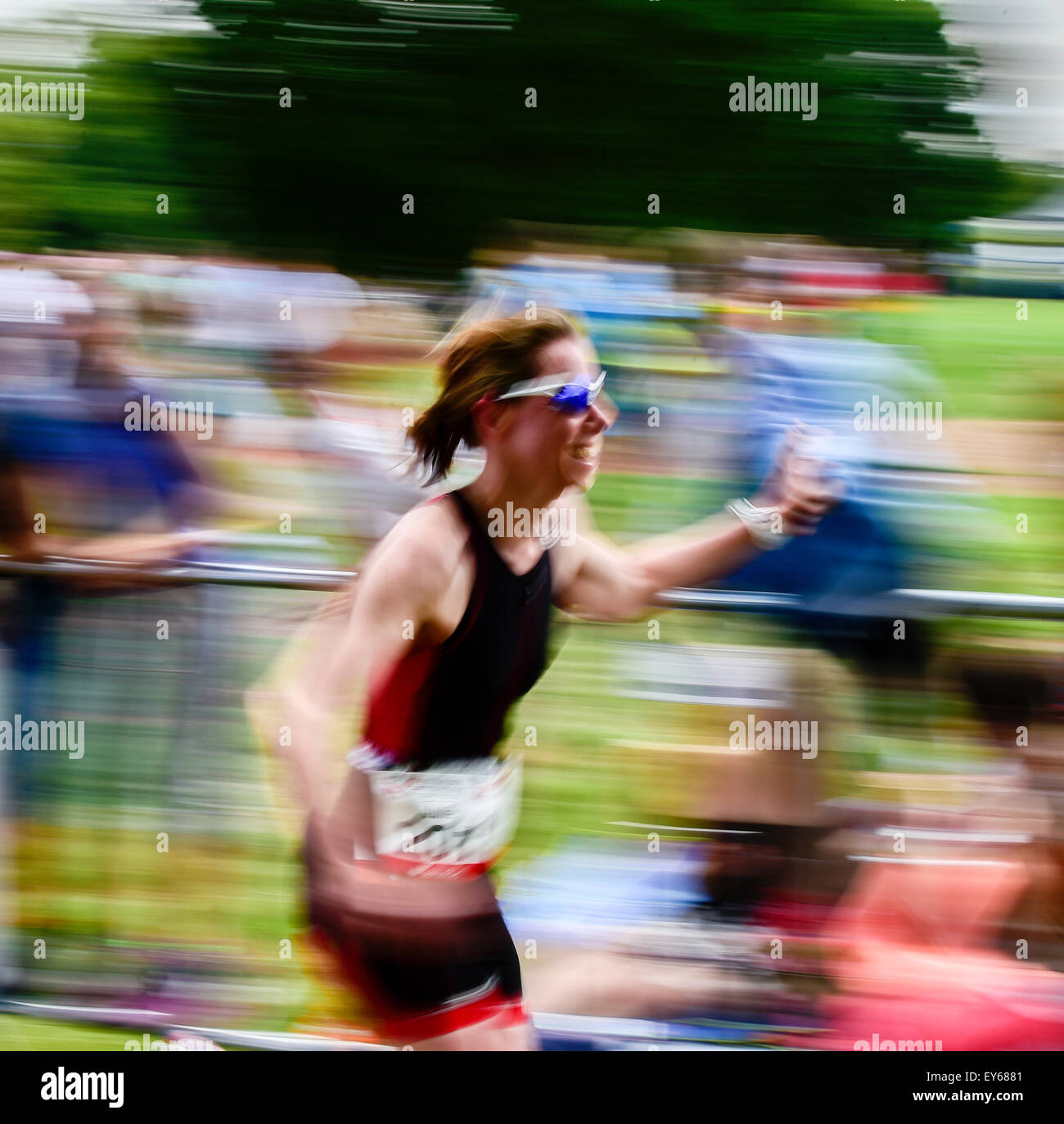 Triathlète féminine célèbre le triathlon avec bouton Jensen Fives élevé alors qu'elle exécute le dernier 100m. Speed image floue. Banque D'Images