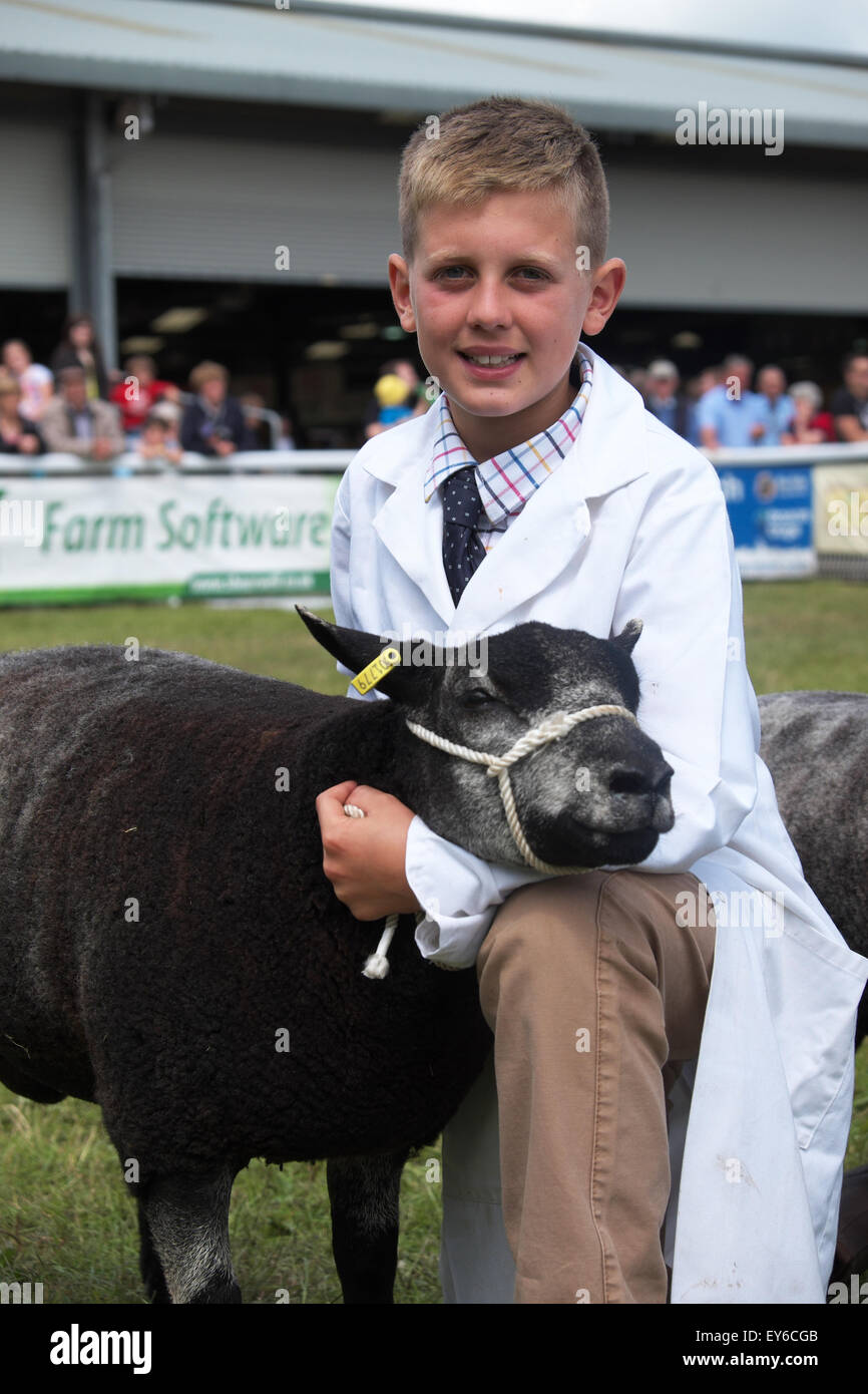 Builth Wells, Powys, Wales, UK. 22 juillet, 2015. Jour 3 - Le soleil brille sur les jeunes Harry Fuller avec son agneau Texel bleu prenant part à l'événement au gestionnaires jeunes Royal Welsh Show. Harry âgée de 10 ans vient de Whitland, Camarthanshire, au Pays de Galles. Les quatre jours de l'événement a attiré plus de 240 000 visiteurs et 7 000 entrées à l'élevage le plus grand salon de l'agriculture. Banque D'Images