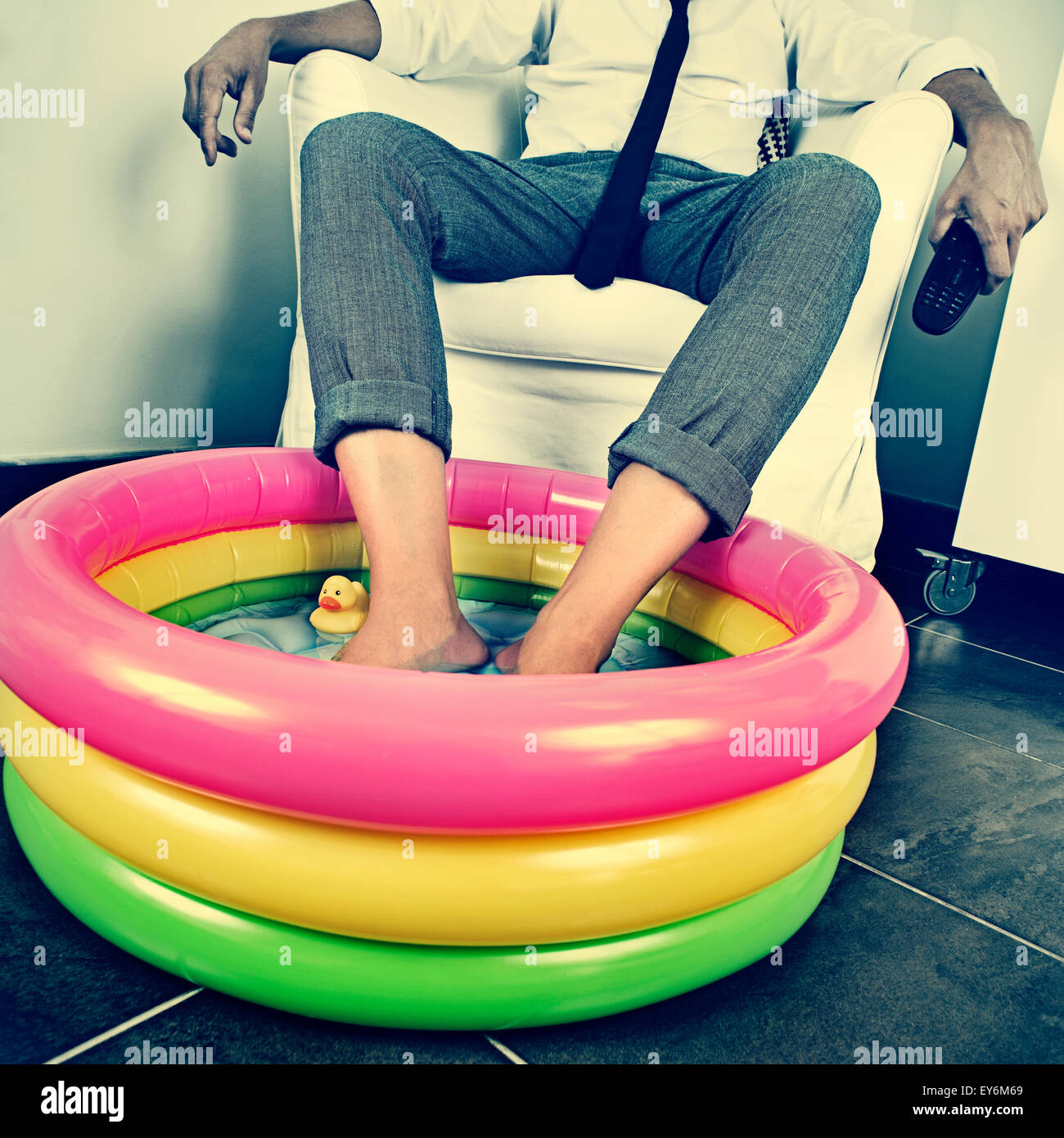 Un jeune homme en fonction de ses pieds tremper dans l'eau d'une piscine gonflable à l'intérieur, avec un effet dramatique, illustrant le concept de stayi Banque D'Images