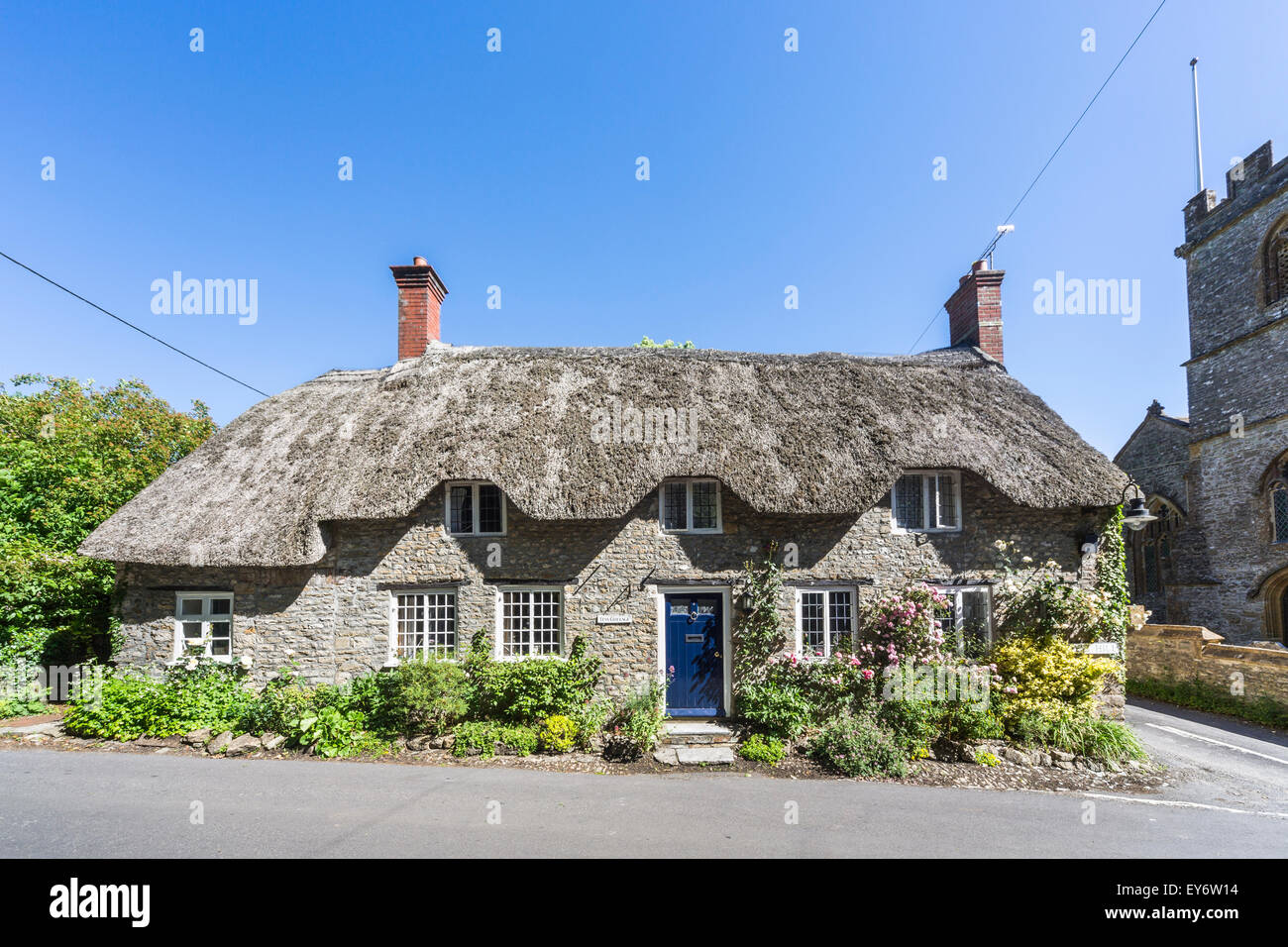 Jolie maison en pierre au toit de chaume, Tess Cottage, Evershot, un petit village dans le Dorset, dans le sud de l'Angleterre, en été avec ciel bleu Banque D'Images