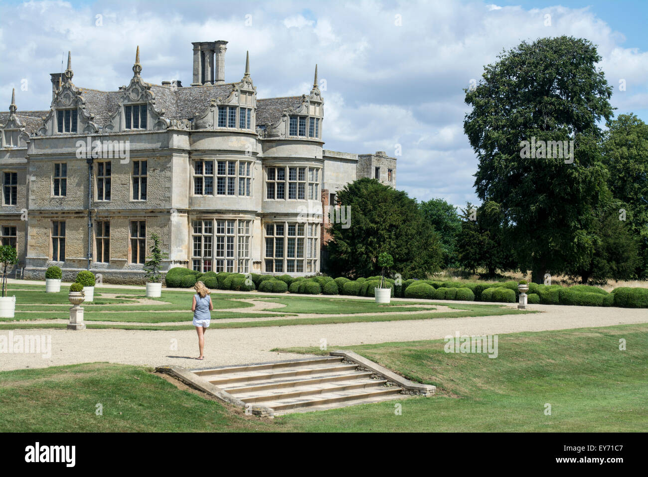 Visiteuse écoute l'audio guide dans les jardins formels à Kirby Kirby Hall Hall, le Northamptonshire, Angleterre Banque D'Images
