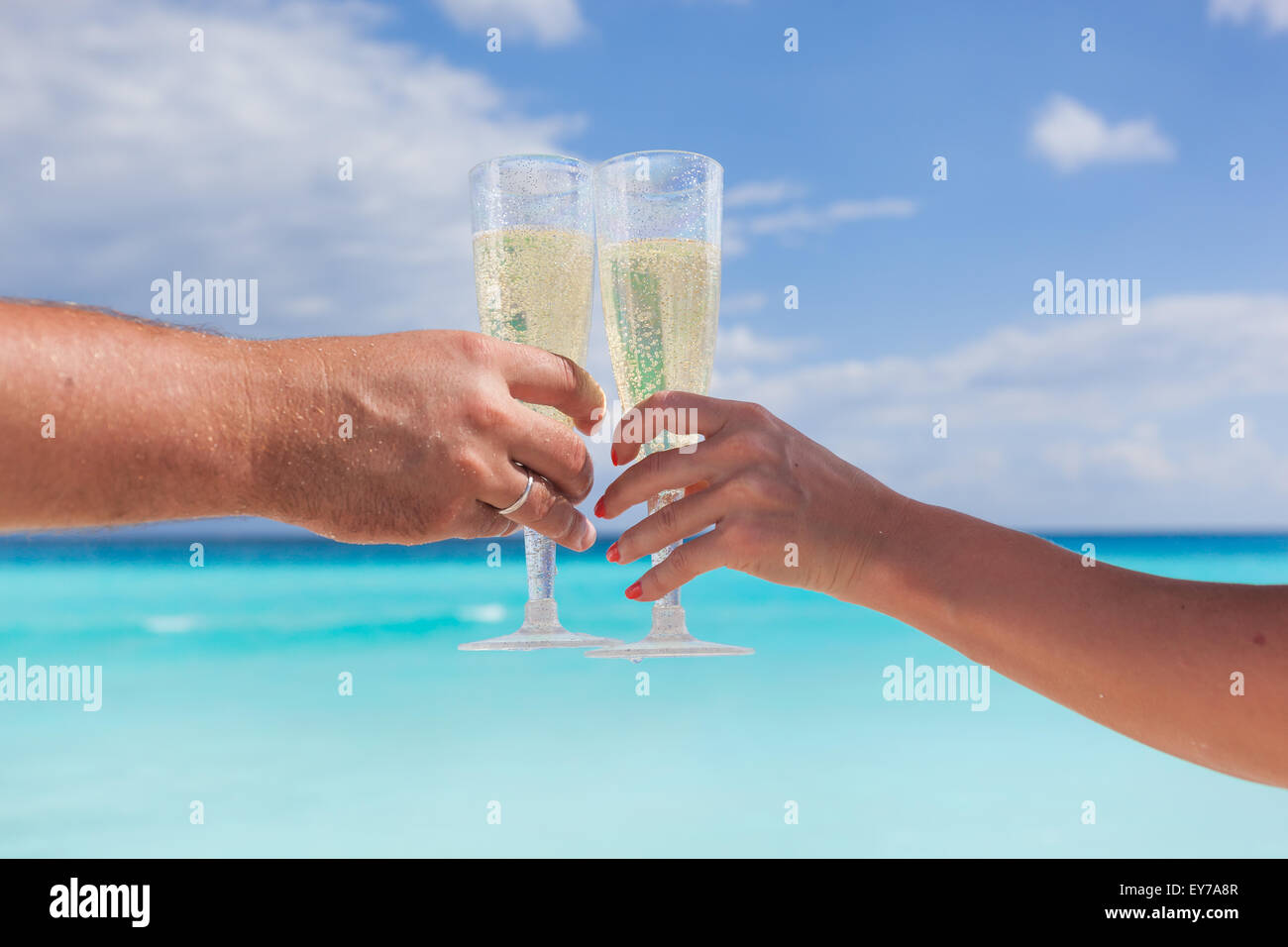 Verres à champagne qui retentit avec plage de sable et de la mer, faible profondeur d'arrière-plan Banque D'Images