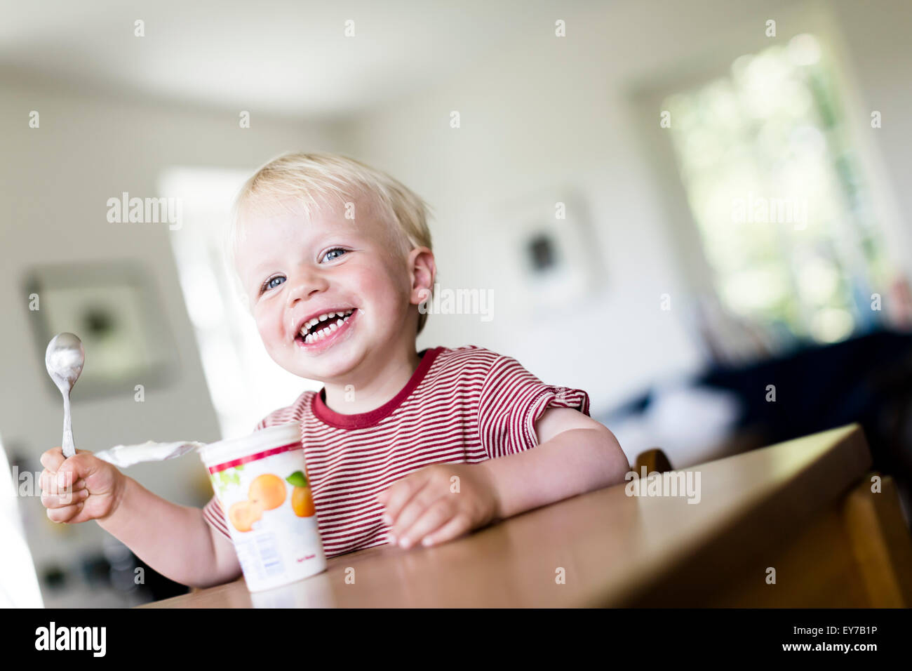 Jeune garçon, 2 ans, manger heureusement un yaourt. Banque D'Images