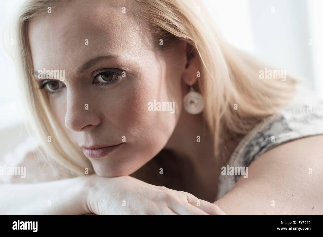 Pensive young woman lying on bed Banque D'Images
