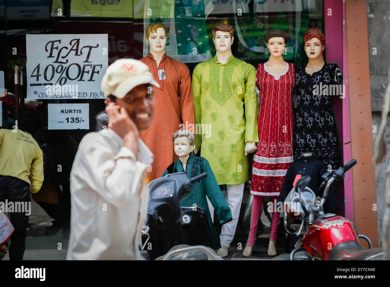 Man using cellphone comme il passe devant fashion store à Varanasi, Inde. Banque D'Images