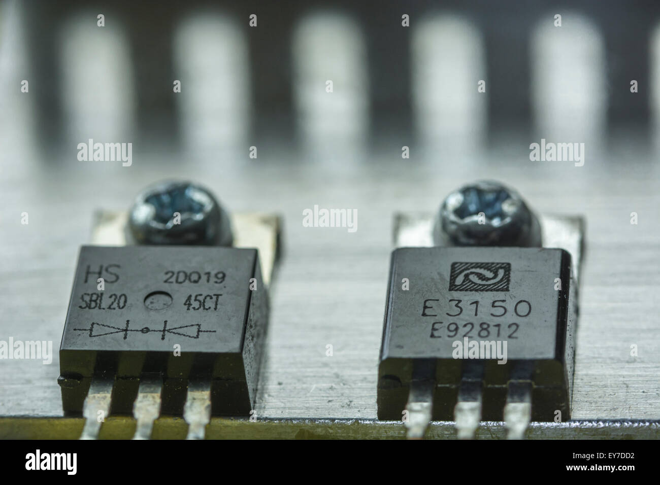 Deux circuits intégrés (CI) vissé à un dissipateur de chaleur en aluminium. Les composants proviennent d'une unité d'alimentation de l'ordinateur. Banque D'Images