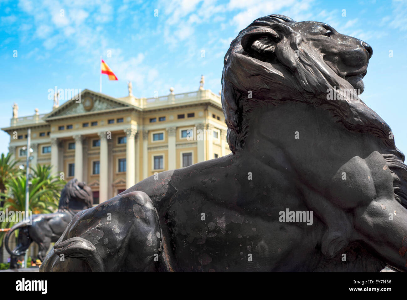 Détail d'un lion de bronze à la base du monument de Christophe Colomb à Barcelone, Espagne, avec la Comandancia bâtiment dans le backgroun Banque D'Images