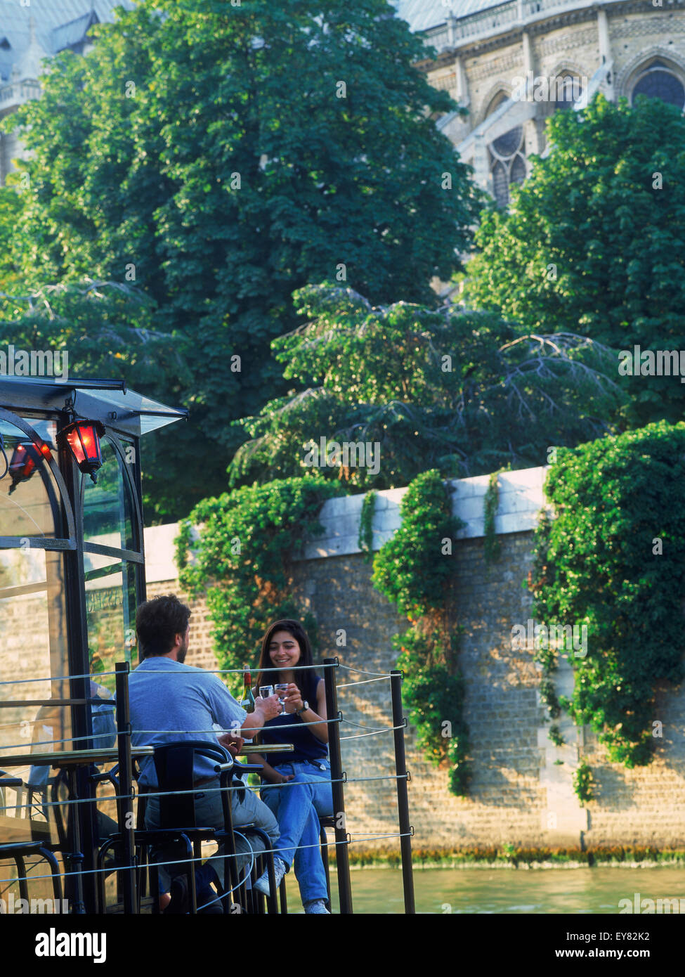 Couple assis sur bateau restaurant sur la Seine à Notre Dame au-dessus d'eux à Paris Banque D'Images