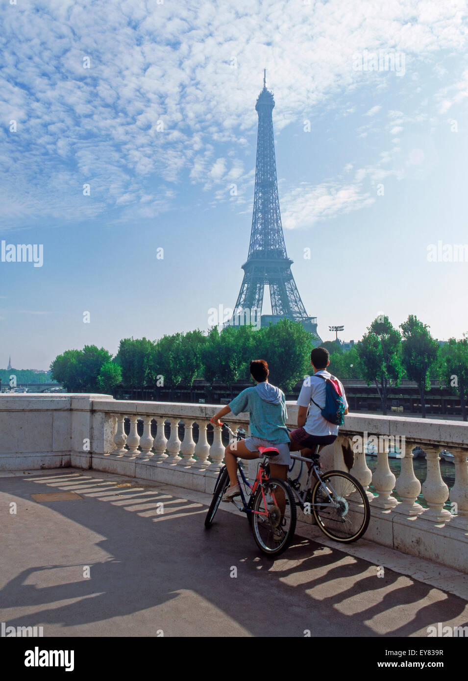 Couple sitting on bikes en regardant vers la Tour Eiffel à Paris Banque D'Images