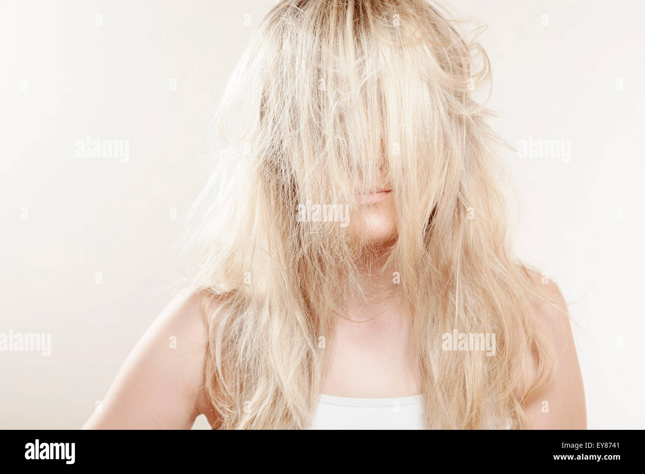Jeune femme, cheveux blonds covering face Banque D'Images